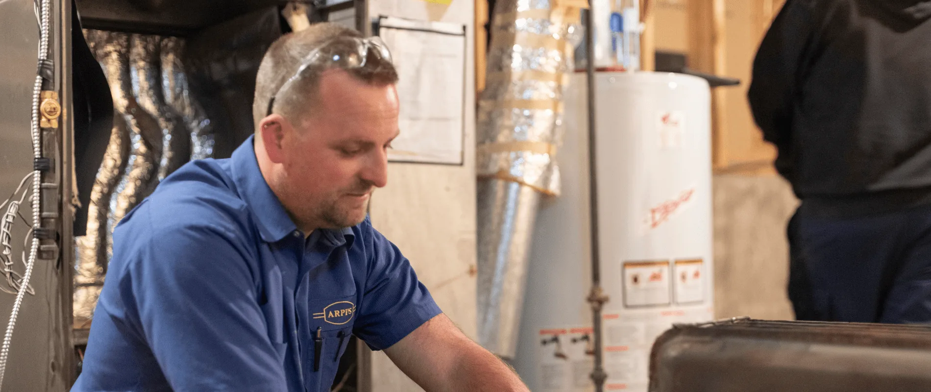 Arpi's technician working near a residential hot water tank during a water heater installation in a Calgary home