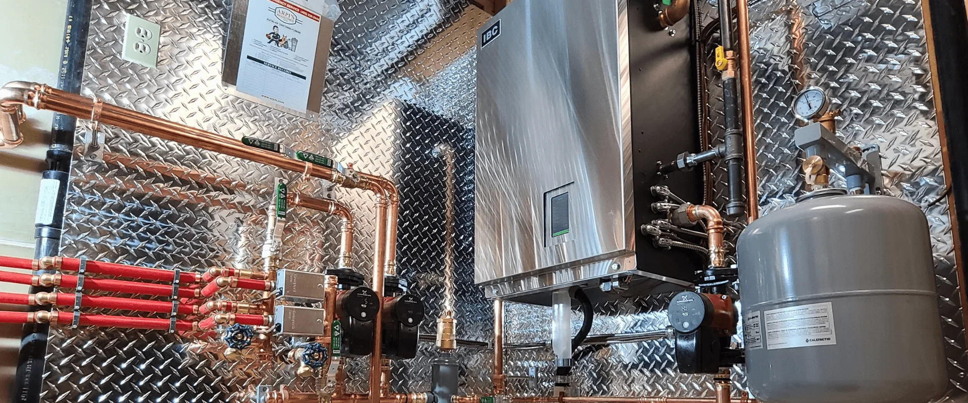 IBC wall-mounted boiler with copper piping, circulator pumps and expansion tank installed by Arpi's in a Calgary home