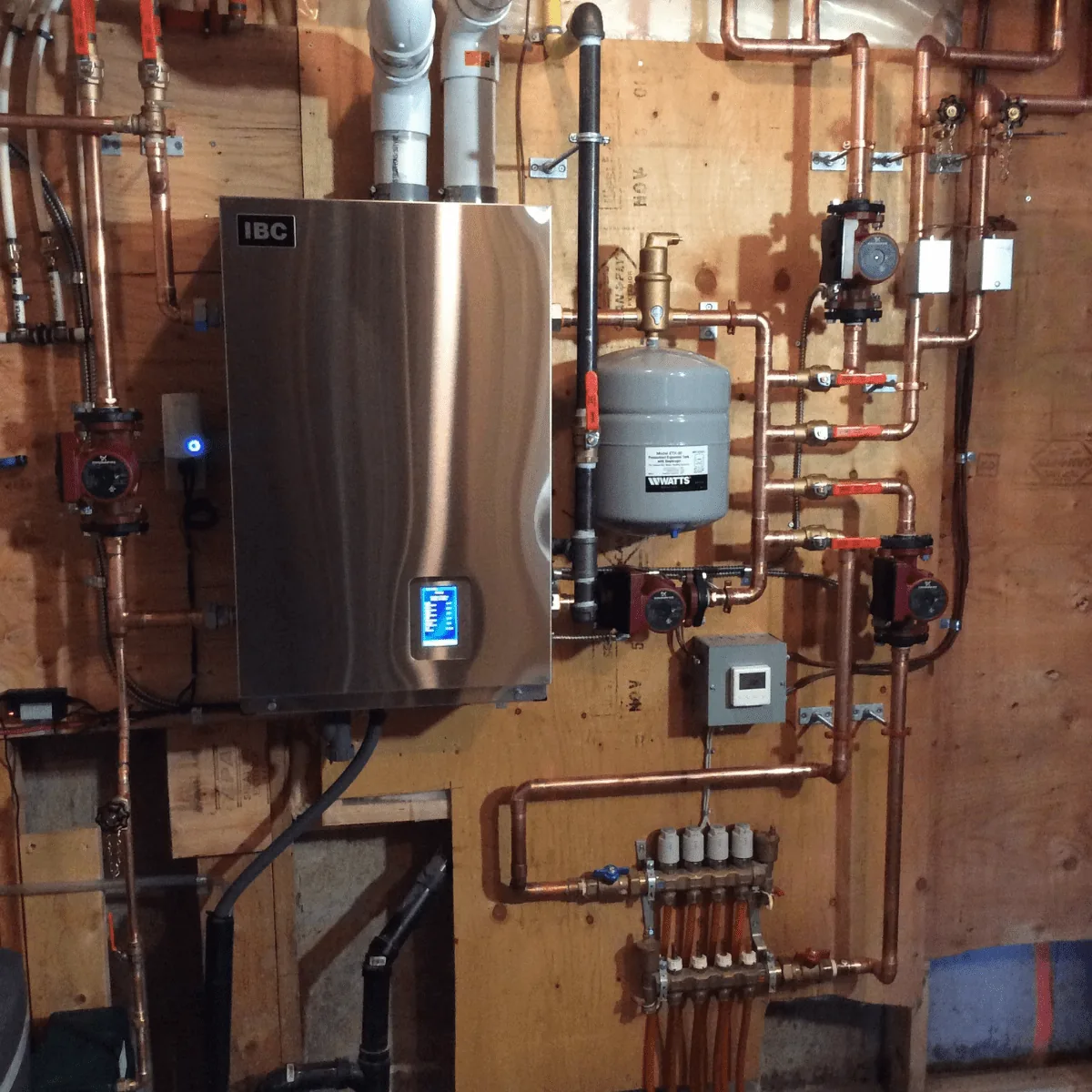 IBC wall-mounted boiler with copper piping, circulator pumps and a Watts expansion tank in a Calgary home serviced by Arpi's