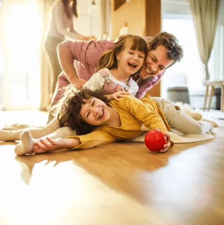 Family playing together on a warm hardwood floor heated by in-floor radiant heating from Arpi's in Calgary