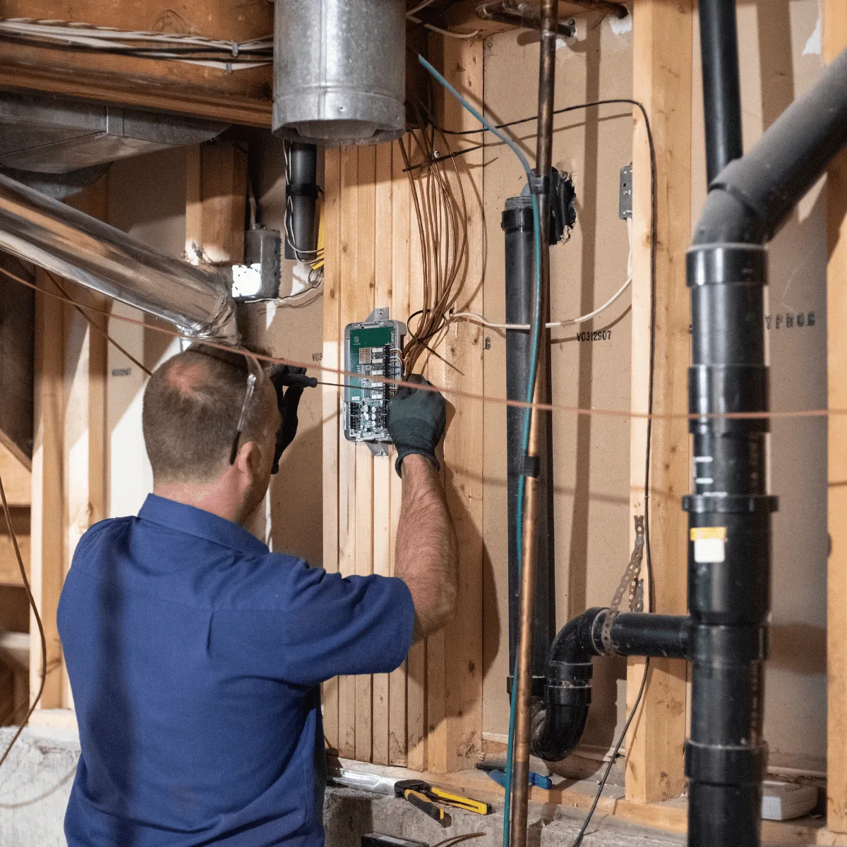 Arpi's technician wiring a control board during a new boiler installation in a Calgary basement