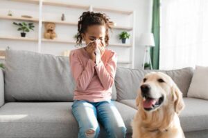 girl sneezing inside because of allergens in the air