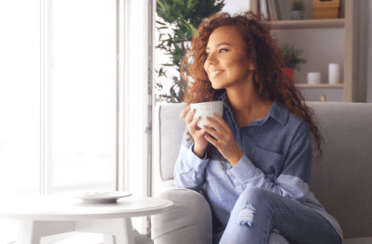 A woman drinks coffee and looks out the window