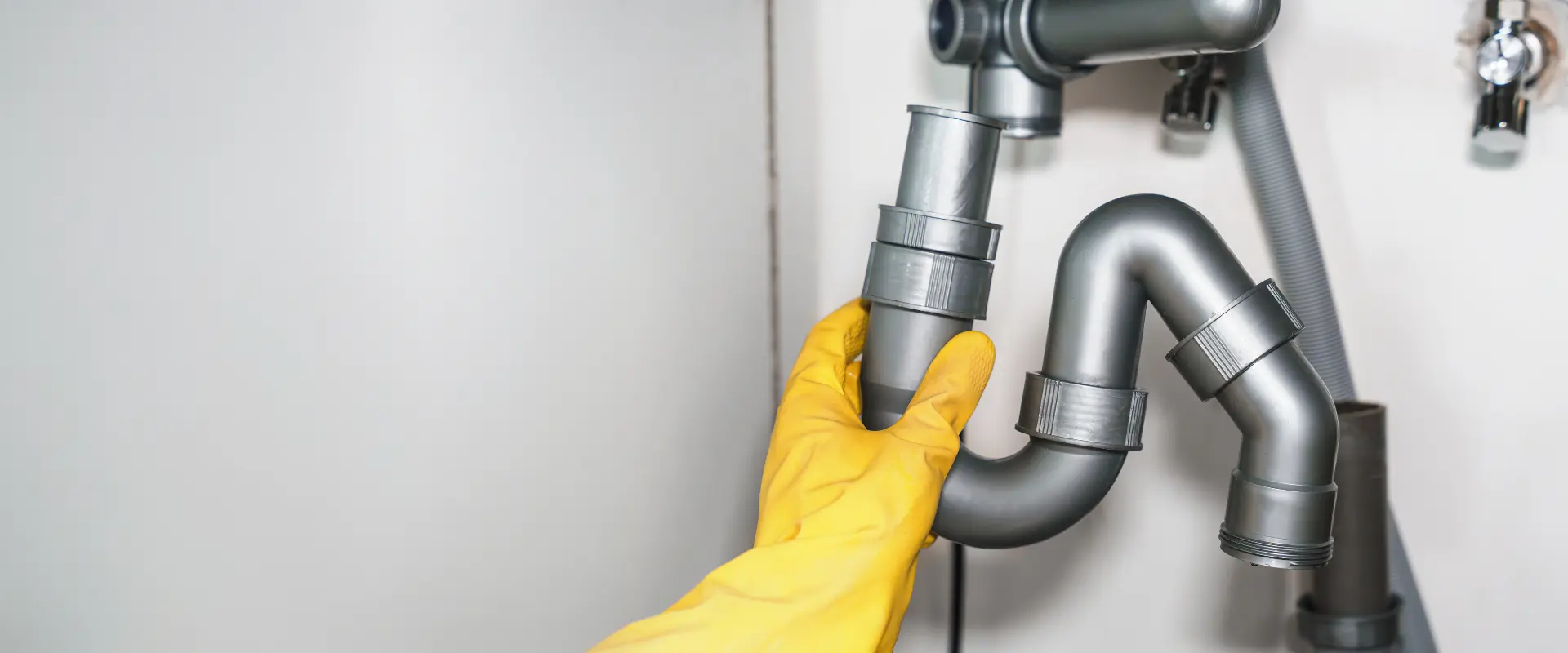 Arpi's Industries plumber inspecting under-sink drain pipes in a Calgary home
