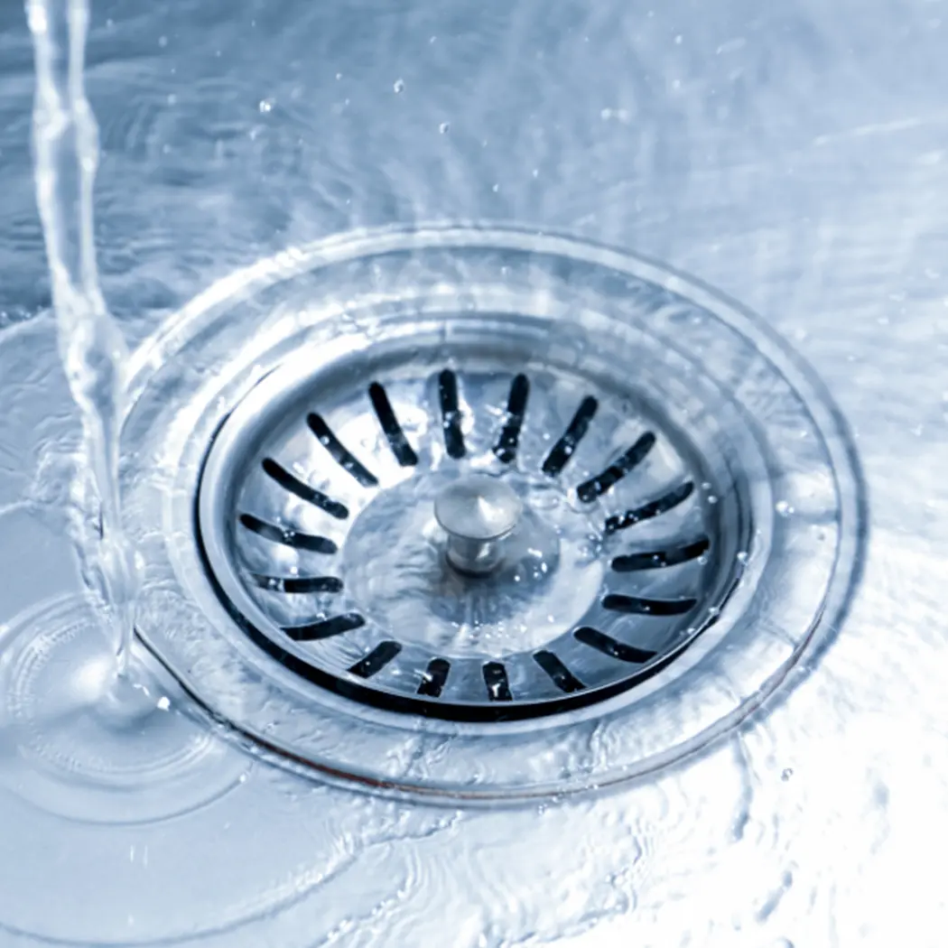 Water flowing freely into a clean kitchen sink drain — Arpi's Industries plumbing services Calgary
