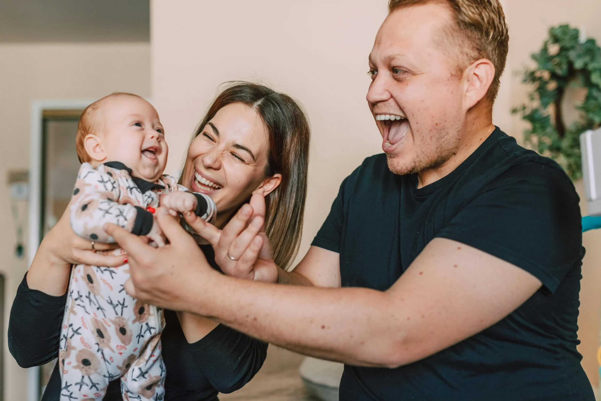 Happy parents playing with their baby at home enjoying reliable hot water comfort from energy-efficient tankless water heaters installed by Arpis.