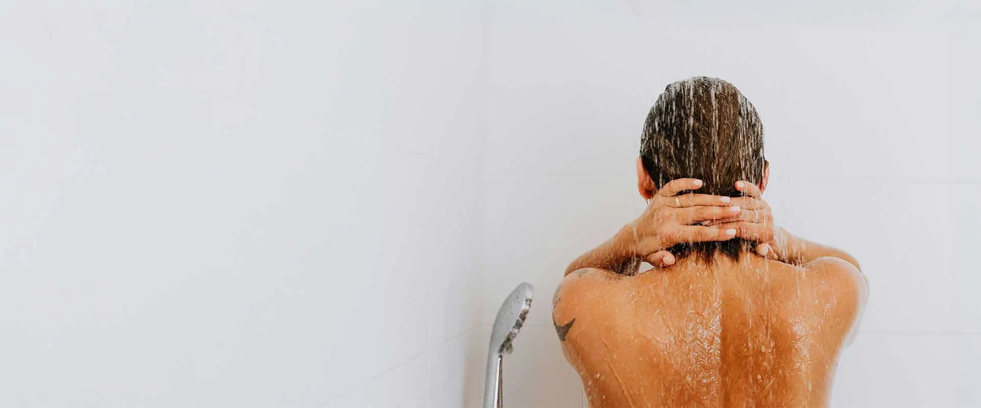 Person enjoying a hot shower with consistent water flow, highlighting reliable comfort from Arpis installations of Navien tankless water heaters.