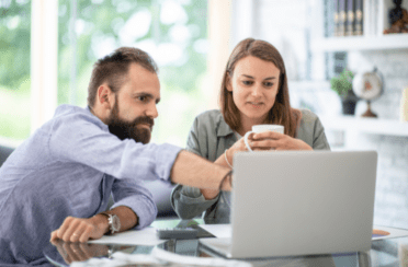 a couple sitting in their kitchen planning the cost of a new furnace installation on the computer