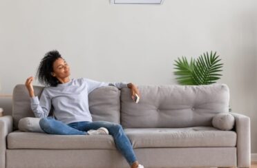 woman sitting on her couch enjoying the comfort of her air conditioning